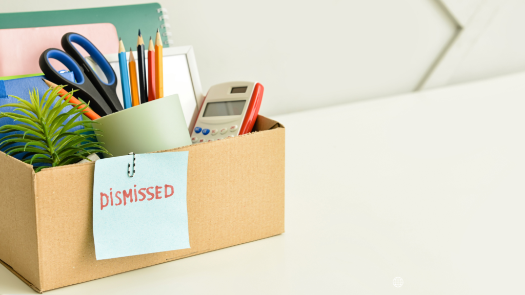 A box labelled 'Dismissed' with office stationery inside and a plant.