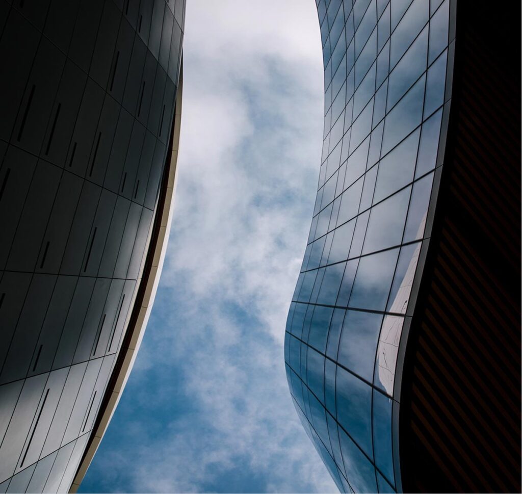 Modern curved glass building reflecting the sky, symbolising transparency and integrity at McLean Partnership.