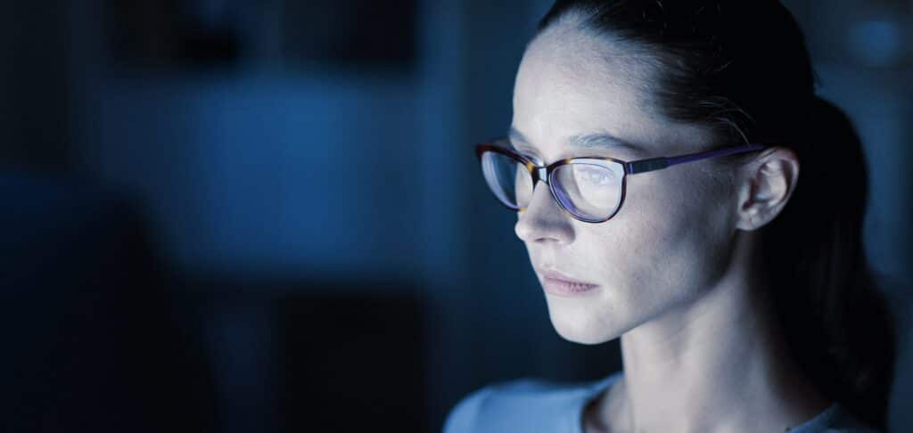 Focused woman in glasses, representing digital expertise in corporate leadership.