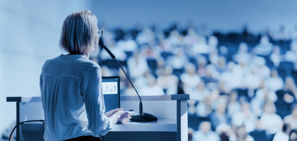 Speaker addressing an audience at a university event, representing academic continuing education leadership.