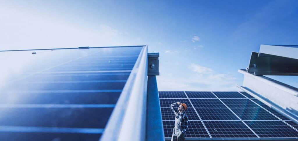 Worker inspecting rooftop solar panels, representing sustainable equity growth.