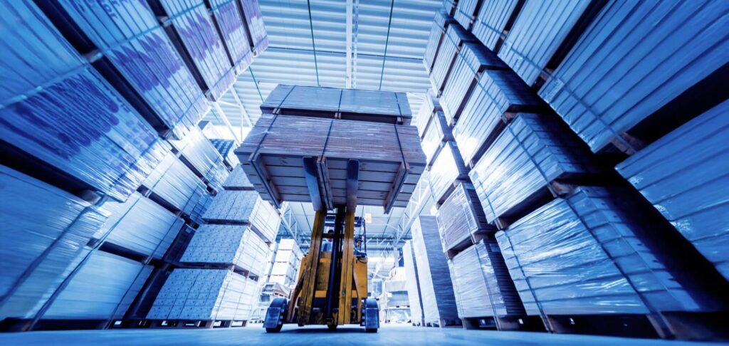 Warehouse interior with stacked goods and forklift, representing financial management in a Swiss manufacturing company backed by private equity in Asia.
