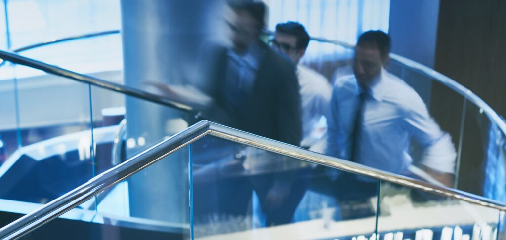 Businesspeople ascending stairs in an office, symbolising collaboration during a UK stockbroking merger.
